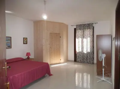 a bedroom with a red bed and a window at Casa Derna 25dx Climatizzata in Castellammare del Golfo