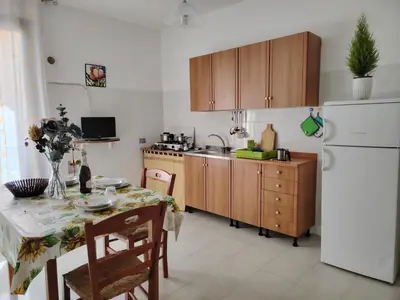 a kitchen with a table and a white refrigerator at Casa Derna 25dx Climatizzata in Castellammare del Golfo