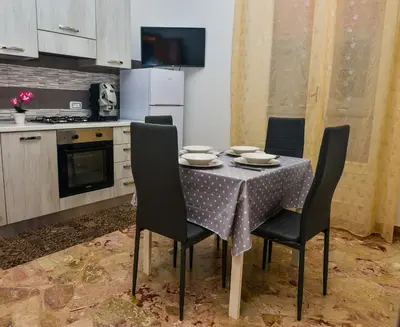 a kitchen with a table with chairs and a refrigerator at Amaryllis Apartments in Bagheria