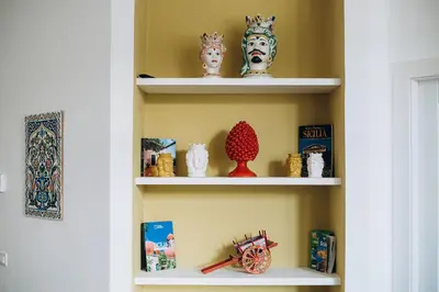 a shelf with statues and books in a room at Doma in Palermo