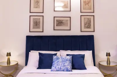 a bed with a blue headboard and framed pictures on the wall at Doma in Palermo