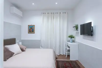 a white bedroom with a bed and a television at OLIVUZZA TOWER in Palermo