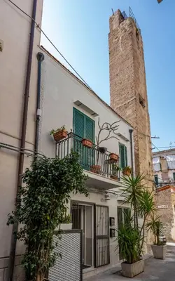 a white building with green shutters and a tower at OLIVUZZA TOWER in Palermo