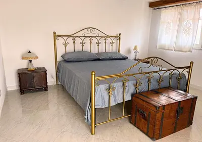 a bedroom with a bed with a metal frame and a table at Villa Finestra sul Castello in Partinico