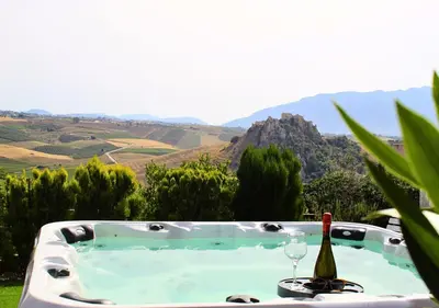 a hot tub with a bottle of wine and a glass at Villa Finestra sul Castello in Partinico