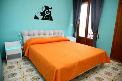 two beds in a room with orange sheets and a sink at villa banksy in Palermo