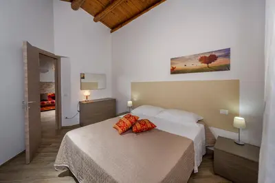 a bedroom with a bed with two red pillows on it at Casetta degli Ulivi Castellammare del Golfo in Scopello