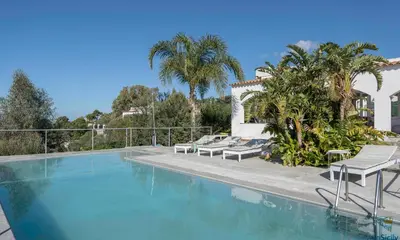 a swimming pool with two lounge chairs and palm trees at Villa Giacona Venuti in Terrasini