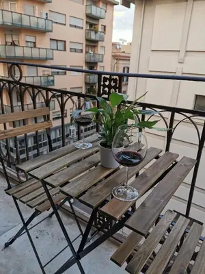a wooden table with a glass of wine on a balcony at Dagnino House - Luxury apartment in the center of Palermo in Palermo