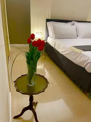 a vase of red flowers on a table next to a bed at Cassari 61 in Palermo