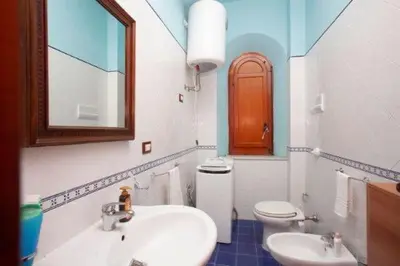 a bathroom with a sink and a toilet and a mirror at Anna&Miky beach house in Santa Flavia