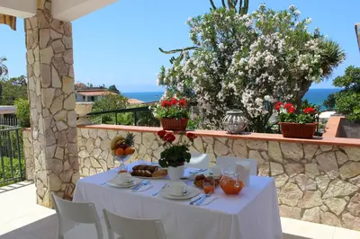 a white table with food and flowers on a balcony at Villa Nàmali just 100 meters from the sea !!! in Trappeto