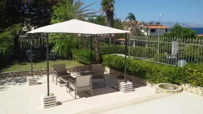 a patio with two chairs and an umbrella at Villa Nàmali just 100 meters from the sea !!! in Trappeto