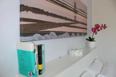a shelf with books and a painting on a wall at Villa Nàmali just 100 meters from the sea !!! in Trappeto