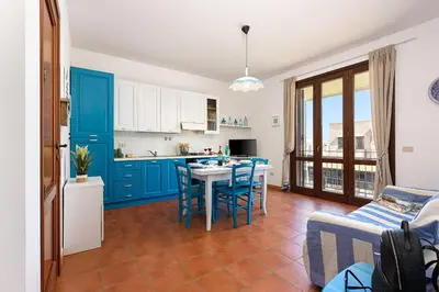 a kitchen with blue cabinets and a table and chairs at Casa Serena in San Vito lo Capo