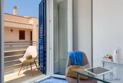 a balcony with a glass table and a chair at Rivazzurra Beach Rooms in San Vito lo Capo