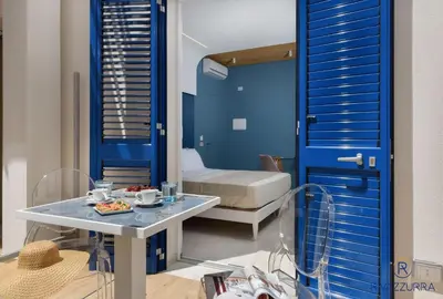 a blue room with a table and a bed at Rivazzurra Beach Rooms in San Vito lo Capo