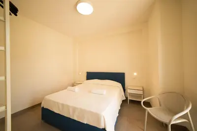 a small bedroom with a bed and two chairs at Blu Home Scopello in Castellammare del Golfo