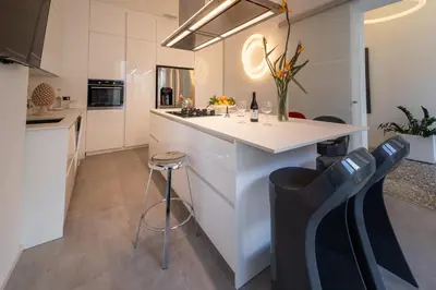 a kitchen with white cabinets and a counter with stools at Casa Slide a Palermo in Palermo