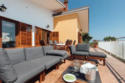 a patio with a couch and chairs on a deck at Appartamento in Villa con accesso al mare, vista mozzafiato in Palermo
