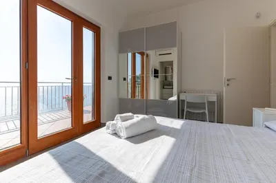 a bedroom with a large bed and a balcony at Appartamento in Villa con accesso al mare, vista mozzafiato in Palermo