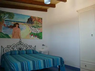 a bedroom with a bed with a painting on the wall at Villetta Edera all'Usciere in San Vito lo Capo