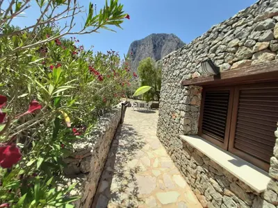 a stone wall next to a building with flowers at Villetta Edera all'Usciere in San Vito lo Capo