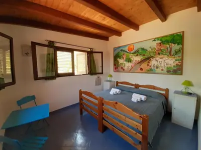 a bedroom with a bed and a table and windows at Villetta Edera all'Usciere in San Vito lo Capo