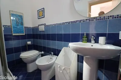 a blue tiled bathroom with a sink and a toilet at Villa Casa di Franca - 700 meters from the sea Scopello in Castellammare del Golfo