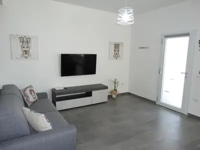 a living room with a couch and a flat screen tv at Villa Milicia - New Private Villa near Palermo and Cefalù with Pool, Sea View Terrace, Playground and Large Parking in Altavilla Milicia