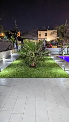 a park at night with a palm tree in the grass at Villa Milicia - New Private Villa near Palermo and Cefalù with Pool, Sea View Terrace, Playground and Large Parking in Altavilla Milicia