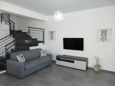 a living room with a couch and a flat screen tv at Villa Milicia - New Private Villa near Palermo and Cefalù with Pool, Sea View Terrace, Playground and Large Parking in Altavilla Milicia