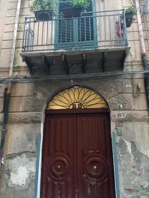 a red door in a building with a balcony at ZU' NICOLA in Palermo