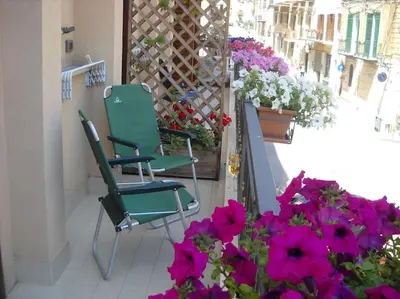 two chairs and flowers on a balcony with flowers at Marconi e Garibaldi 76 apartment in Castellammare del Golfo