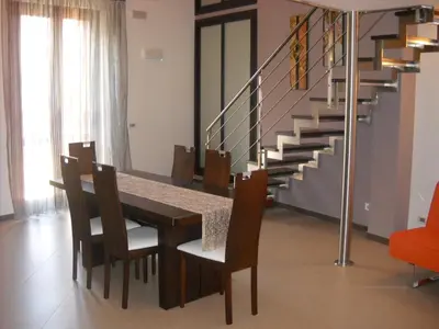 a dining room with a table and chairs and stairs at Marconi e Garibaldi 76 apartment in Castellammare del Golfo