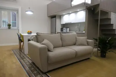 a living room with a couch and a kitchen at Opera Suites - Aida in Palermo