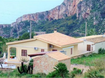 a house with a mountain in the background at Villa Contrada Sauci in San Vito lo Capo