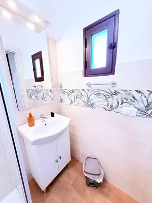 a white bathroom with a sink and a mirror at Casa vacanza CUTÓ in Bagheria