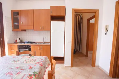 a kitchen with a table and a white refrigerator at SanVitoTour- Appartamento Smeraldo in San Vito lo Capo