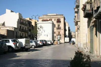 a city street with parked cars and buildings at A terrace in the heart of Palermo in Palermo