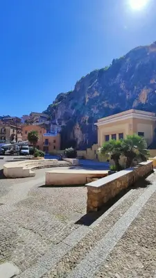 a stone bench in front of a building with a mountain at Il Principe casa vacanze in Trabia