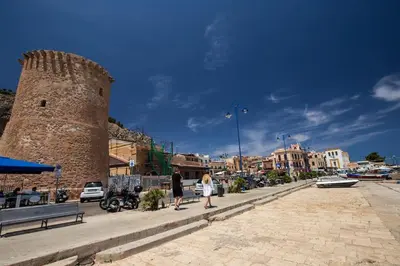 two people walking down a street next to a tower at casa di Enrico in Palermo