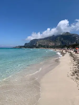 a beach with people walking on the sand and the ocean at Daziarosetta in Palermo