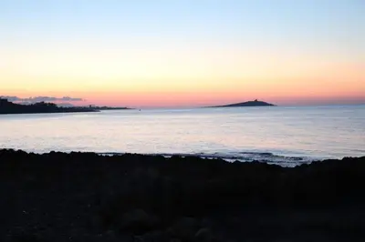 a sunset over the ocean with an island in the distance at VILLA DELLE POMELIE in Isola delle Femmine