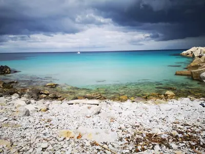 a view of the beach with a boat in the water at APPARTAMENTO A SAN VITO LO CAPO STANZA CON BAGNO in San Vito lo Capo