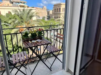 a balcony with two chairs and a table with flowers on it at Case Orlando_a city center Sicilian treat in Palermo