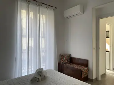 a bedroom with a bed and a chair and a window at Case Orlando_a city center Sicilian treat in Palermo