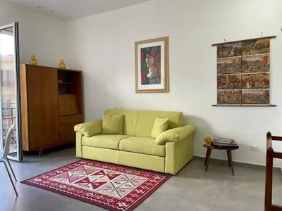 a living room with a green couch and a red rug at Case Orlando_a city center Sicilian treat in Palermo