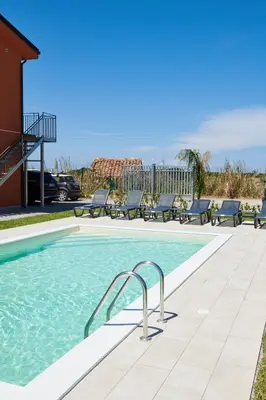 a swimming pool with benches next to a building at Salinelle Rooms in Lascari