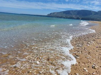 a beach with rocks and water with mountains in the background at Villa Mare Ercole Luxury in Trappeto
